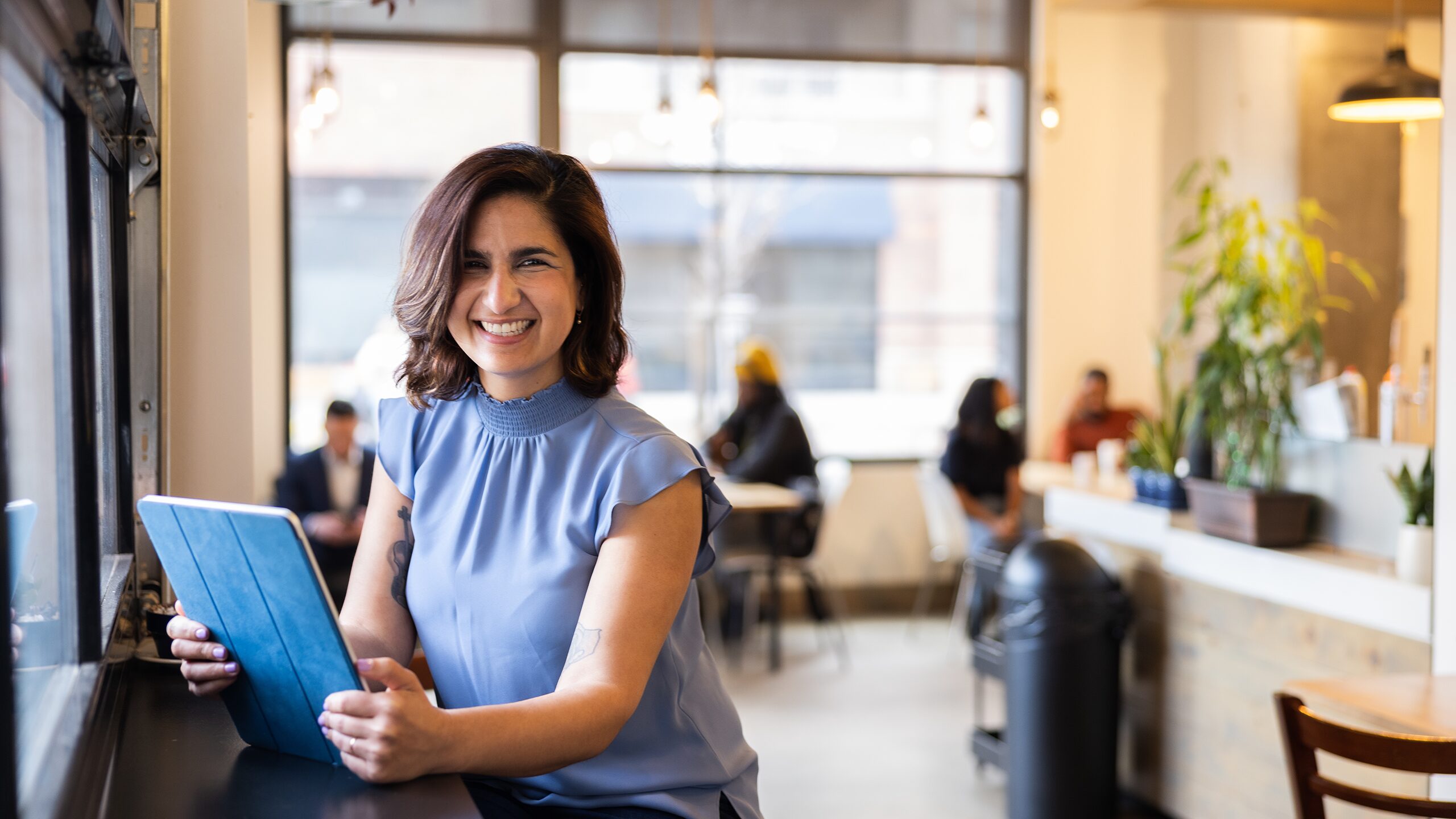 Woman holding a tablet in a cafe.